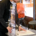 smittevegg står som skillevegg på et bord i en restaurant